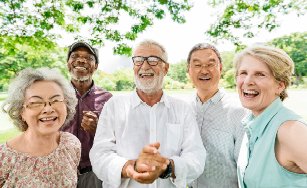 seniors standing outside by a tree smiling at the camera. 