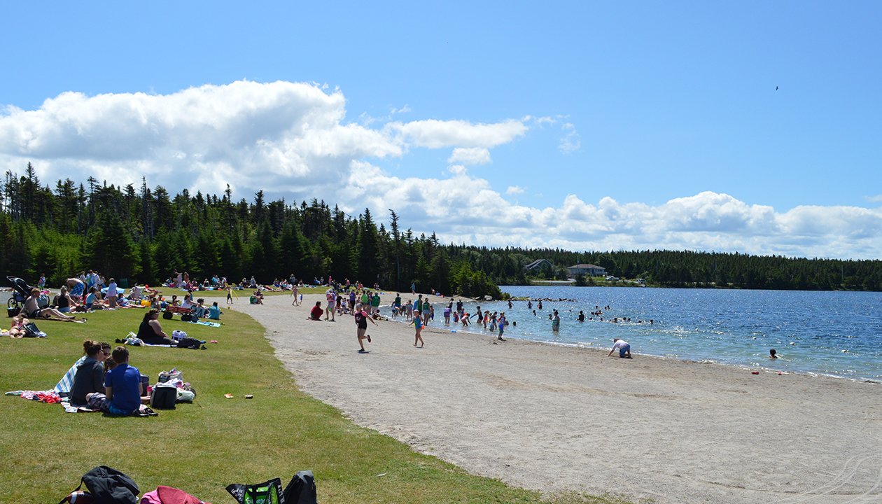 View of people enjoying Rotary Sunshine Park beach on Healeys Pond on a sunny day