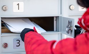 Image of a person putting mail in a community mailbox