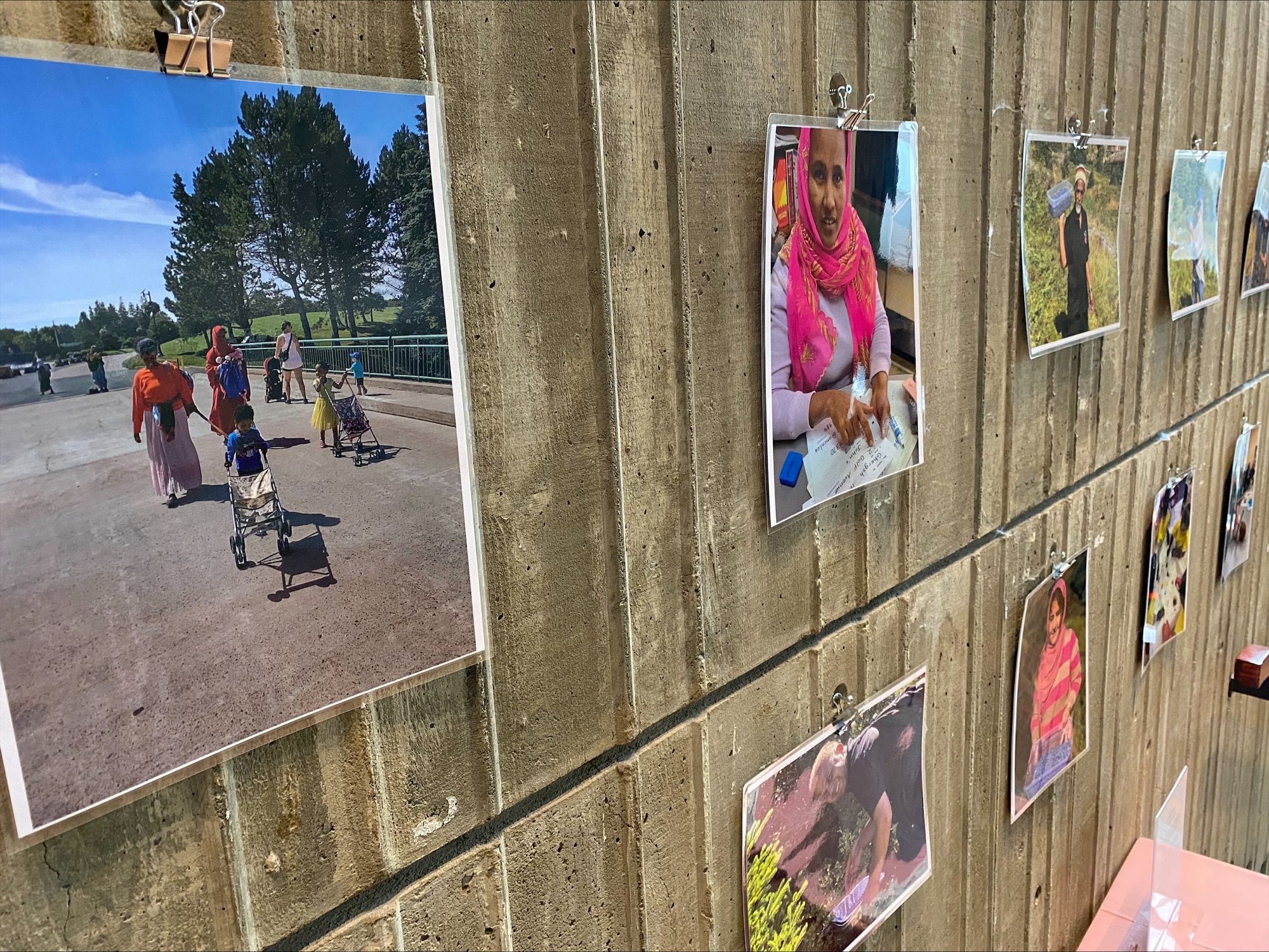 image of photos hanging from clips along the concrete wall at City Hall